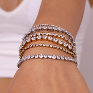 Dettaglio di bracciali tennis sovrapposti in oro e argento con zirconi sul polso
