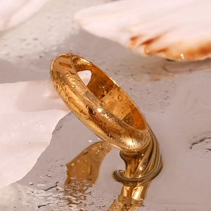Macro shot of 18K gold plated thick dome ring with water drops on mirrored surface