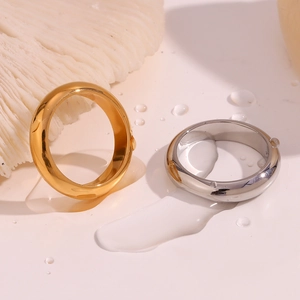 Polished gold and silver thick bands displayed on a minimalist background with water drops