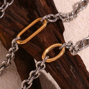 Detail view of two-tone stainless steel cable chain necklace draped on wood texture
