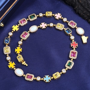 Dettaglio di una collana con pietre preziose colorate e croci smaltate su seta blu