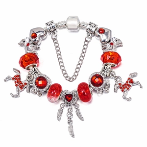 Detalle de cuentas de cristal rojo y dijes de caballo en pulsera de cadena plateada