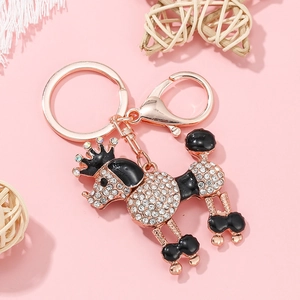 Détail macro du porte-clés caniche en strass avec finition or rose sur fond rose