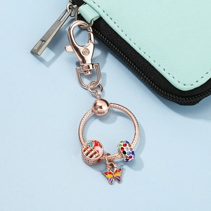 Rose gold keychain with colorful rhinestone charms and enamel butterfly on a cyan leather bag