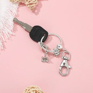 Silver alloy charm keychain with beads and lobster clasp on a pink background