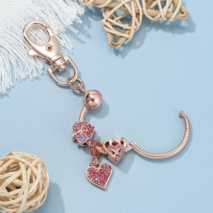Portachiavi in oro rosa con ciondoli a cuore e foglia d'acero scintillanti su blu