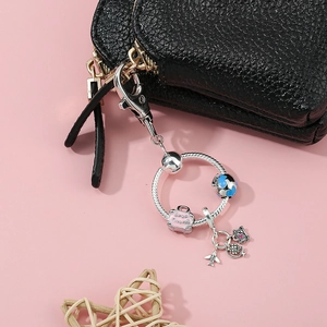 Travel theme keychain with airplane, suitcase, globe pendants on black leather purse
