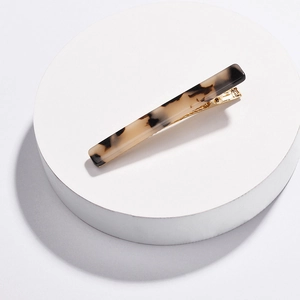Macro detail of tortoiseshell acrylic hair clip with steady gold-toned metal fastener