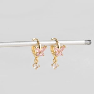 Détail de boucles d'oreilles créoles dorées 18 carats avec breloques papillon en zircon