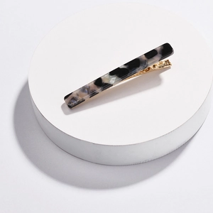Detailed macro of marble pattern acrylic hair clip with a sleek golden metal base