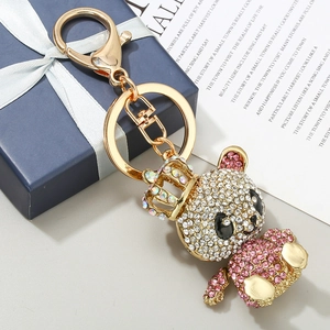 Porte-clés singe doré avec couronne et strass sur un coffret cadeau bleu