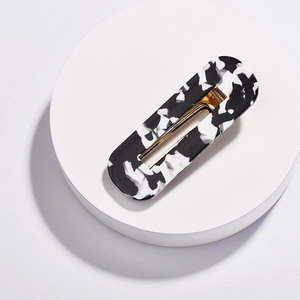 Macro detail of marble pattern acrylic hair clip with internal golden metal fastener