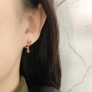 Gros plan d'une boucle d'oreille papillon en or 18 carats avec zircons roses sur l'oreille