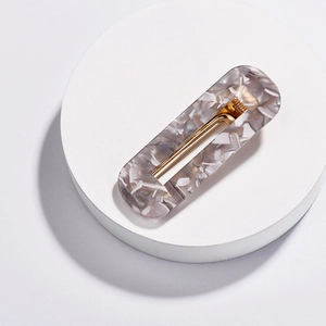 Macro detail of rectangle acrylic hair clip with grey marble texture and gold metal grip