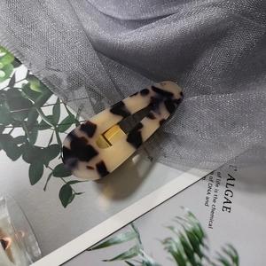 Detail of tortoise shell acrylic hair clip with metallic snap and leopard pattern