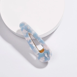 Macro detail of blue marble texture acetate hair clip with golden metal fastener