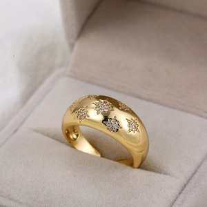 Macro-opname van een vergulde dikke ring met stervormige zirkonia-inlays en gepolijste glans