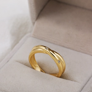 Detail van 18K gouden ring met vlechtontwerp en kleine diamanten op een juwelendoos