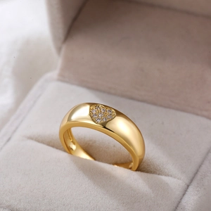 Detail van een brede 18K gouden ring met een hartvormige zetting van zirkonia-stenen