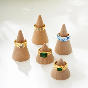 Détail de bagues plaquées or 18 carats avec pierres vertes sur supports en bois