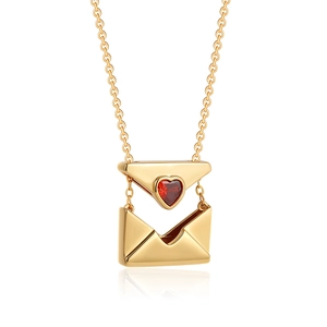 Macro view of gold envelope locket necklace with red heart zircon and shiny metal finish