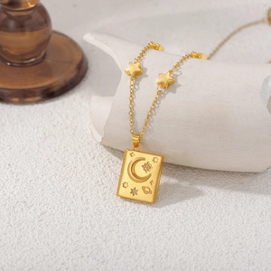 Detail of 18K gold necklace with celestial moon and star patterns on rectangle pendant