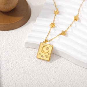 Macro detail of 18K gold book pendant with moon, stars, and white zircon on a chain