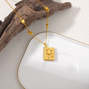 Close-up of 18K gold star necklace with moon and planet engraved book-shaped locket pendant