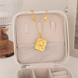 Macro view of a gold celestial book pendant necklace inside a soft beige velvet jewelry box