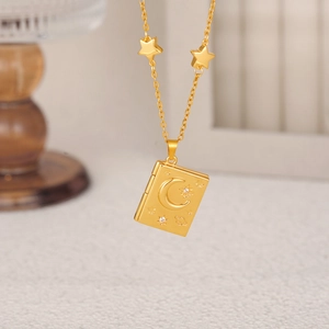 Macro shot of 18K gold book pendant with celestial moon and star motifs and rhinestones
