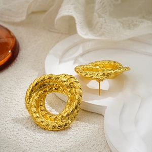 Detalle de pendientes de nudo trenzado dorado con textura vintage y acabado brillante