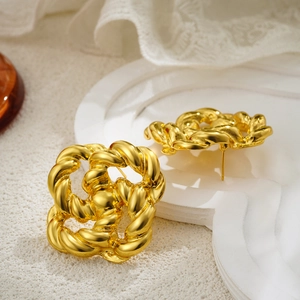 Detalle de pendientes retro bañados en oro de 18 quilates con textura trenzada y nudos