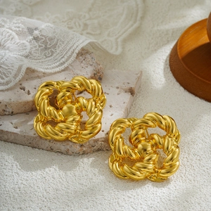 Detalle de pendientes trenzados de oro de 18K sobre una elegante superficie de piedra