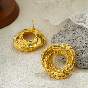 Detalle de pendientes retro de oro 18K con nudo de cuerda sobre un fondo de piedra