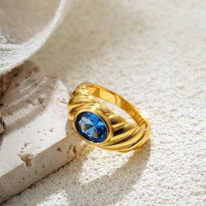 Macro detail of 18K gold vintage ring featuring blue oval zircon and spiral texture