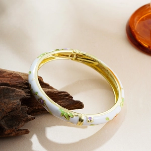 Detail of 14K gold enamel bracelet with white finish and colorful floral patterns
