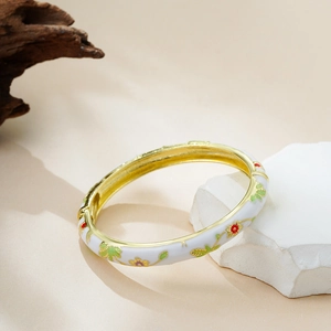 Close-up of 14K gold enamel bangle featuring colorful hand-painted floral motifs