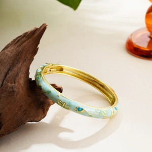 Detailed close-up of 14K gold enamel flower bangle with spring open cuff design