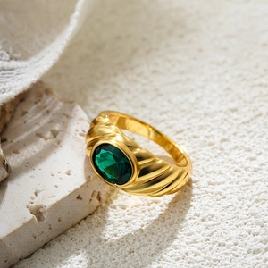 Macro view of a 18K gold croissant ring with a large oval emerald green zircon stone