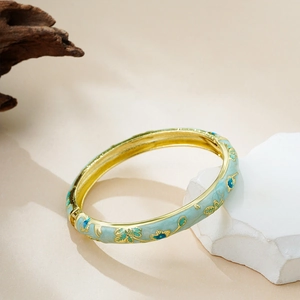 Macro shot of 14K gold-plated floral cloisonne enamel bangle with spring hinge mechanism