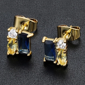 Detailed macro view of 18K gold earrings with blue, yellow, and white zircon stones