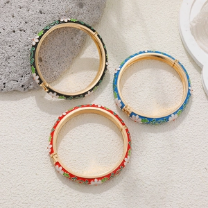 Detail of 14K gold-plated enamel floral bangles in red, black, and blue finishes