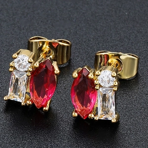 Detailed macro view of 18K gold earrings with red marquise and clear square zircons