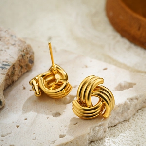 Vista macro degli orecchini a nodo in oro 18 carati su vassoio in pietra