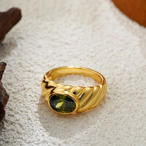 Macro view of vintage 18K gold ring featuring an oval green gemstone and twisted band