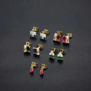 Detailed macro view of five pairs of 18K gold earrings with colorful zircon gemstones