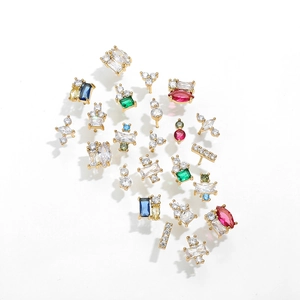 Macro detail of 18K gold earrings with colorful zircon stones in various geometric shapes