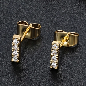 Detail of 18K gold bar earrings with four vertically set cubic zirconia on black leather