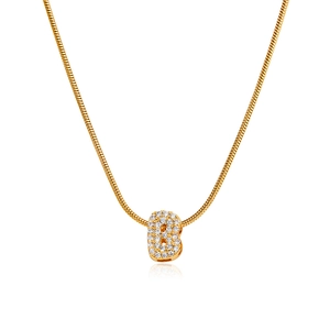 Macro shot of 18K gold letter B pendant with micro-pave cubic zirconia on snake bone chain