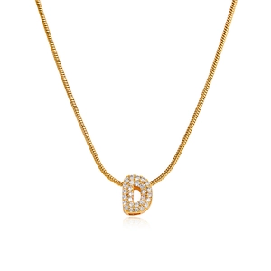 Macro detail of 18K gold letter D pendant with micro-pave cubic zirconia inlay